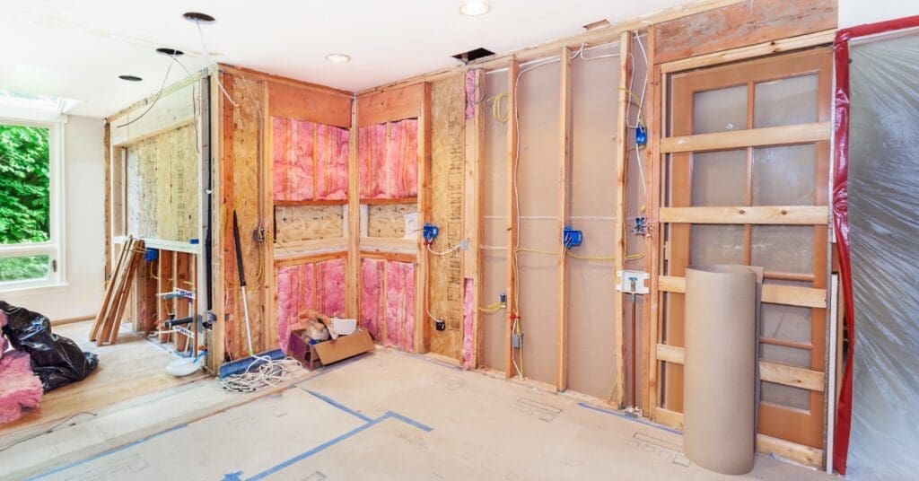 A kitchen's walls became demolished and are taken down to the studs. There's pink insulation showing in the walls.